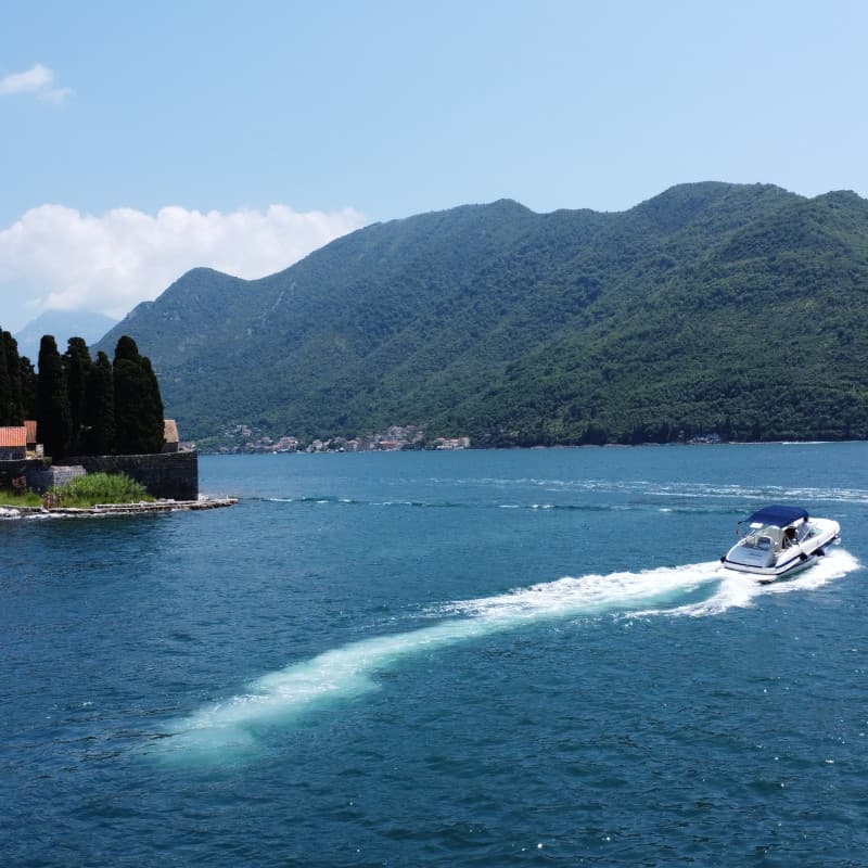 Boat sailing around an island with a mountain in the background